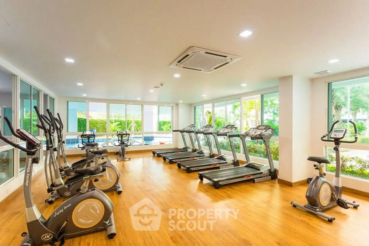 Spacious gym with modern equipment and large windows offering garden views.