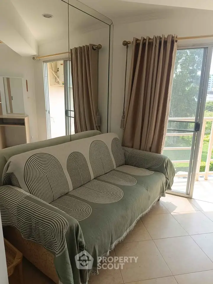 Cozy living room with stylish sofa and balcony access, offering natural light and serene views.