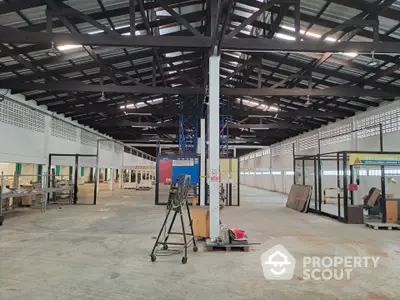 Spacious industrial warehouse interior with high ceilings and ample natural light.