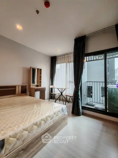 Modern bedroom with balcony access in a stylish apartment, featuring natural light and contemporary furnishings.