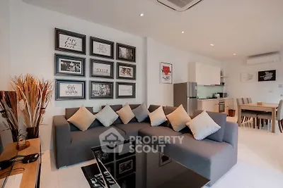 Modern living room with stylish decor and open kitchen layout, featuring a cozy sectional sofa and framed wall art.