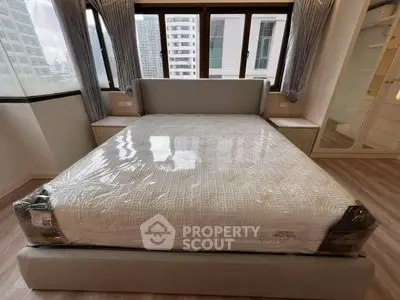 Modern bedroom with large windows and new mattress in urban apartment