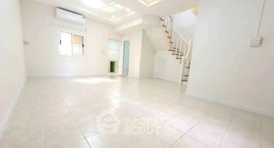 Spacious and bright living room with staircase and air conditioning in modern home.