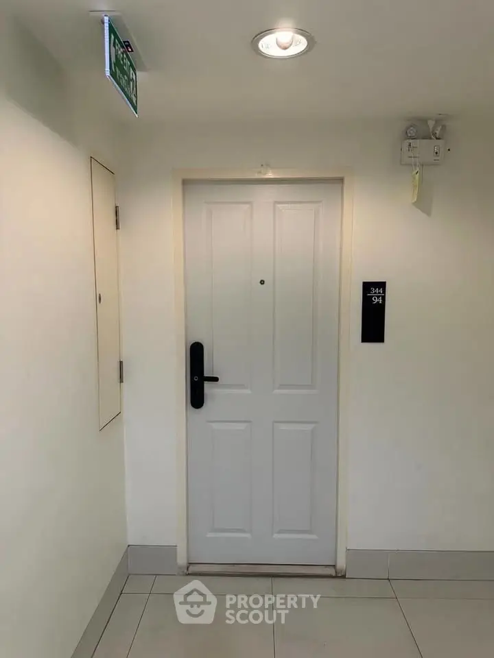 Modern apartment entrance with sleek white door and digital lock