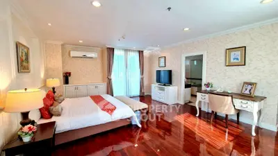 Luxurious bedroom with elegant decor and polished wooden floors, featuring a cozy bed, stylish desk, and ample natural light.