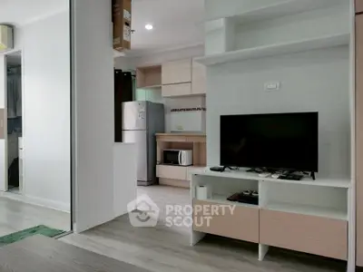 Modern living room with sleek TV stand and open kitchen layout in stylish apartment.