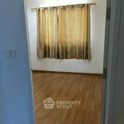 Spacious empty room with wooden flooring and elegant curtains, perfect for customization.