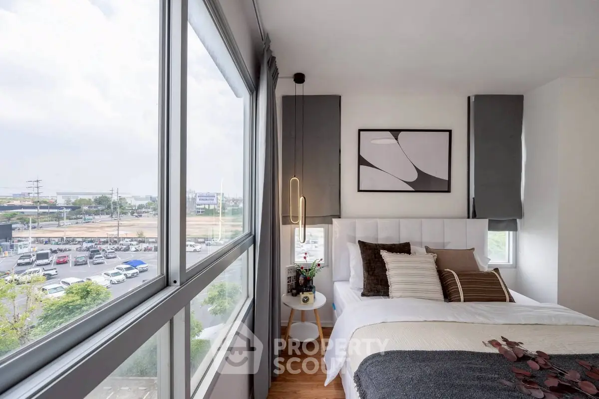 Modern bedroom with large windows offering a stunning city view, stylish decor, and cozy ambiance.