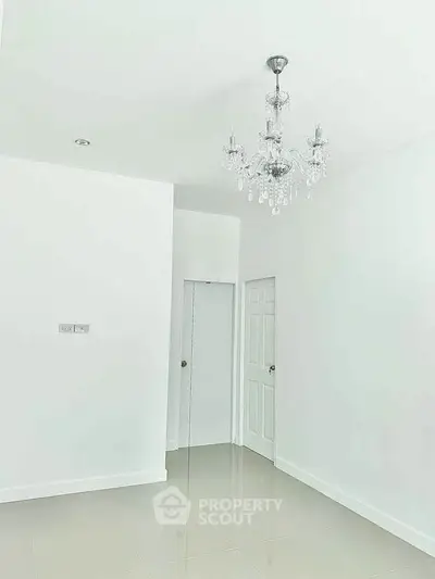Minimalist white room with elegant chandelier and glossy tiled floor