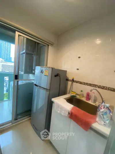 Compact kitchen with modern appliances and balcony view in urban apartment