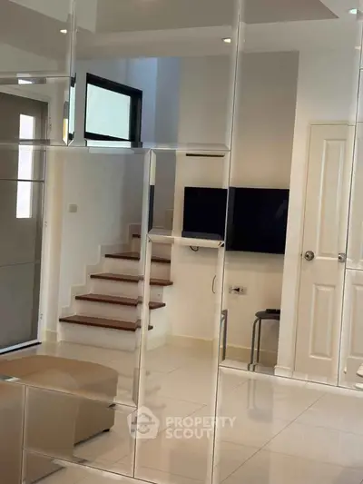 Modern living room with sleek staircase and wall-mounted TV in a stylish home interior.