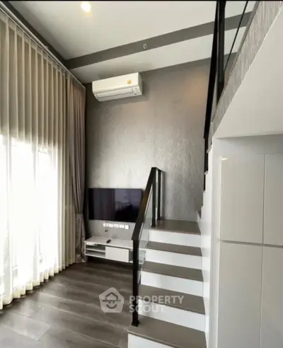 Modern loft-style living room with high ceilings and sleek staircase