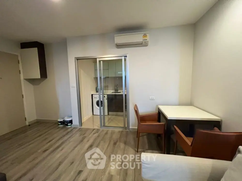 Modern living room with sleek flooring and compact laundry area