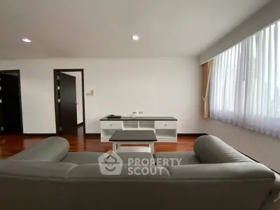 Spacious living room with modern sofa and large window, perfect for relaxation.