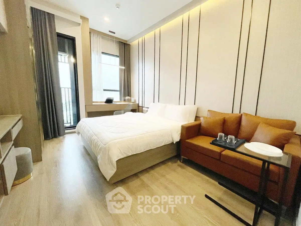Modern bedroom with cozy bed, stylish sofa, and balcony access in a chic apartment.