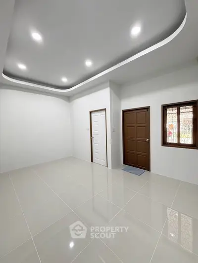 Spacious modern room with sleek tile flooring and elegant ceiling design.