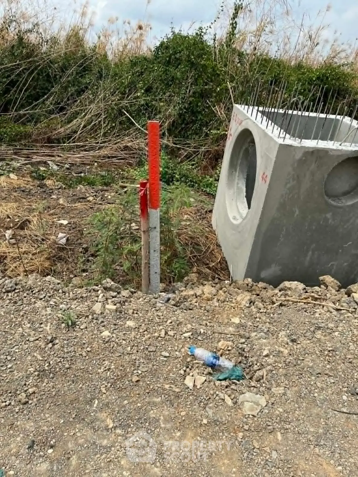Construction site with concrete structure and marked pole, showcasing development potential.
