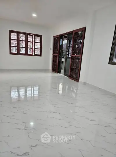 Spacious living room with marble flooring and large windows for natural light.