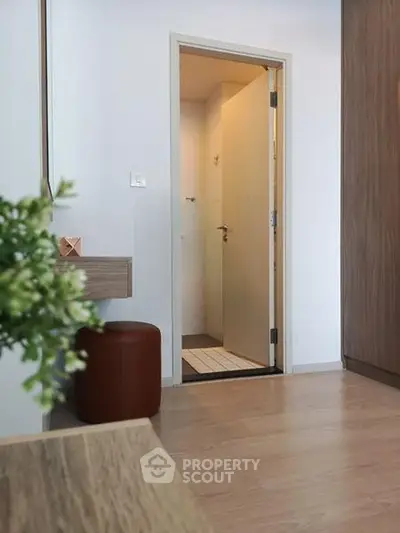 Modern interior with open door leading to a bathroom, featuring wooden flooring and contemporary decor.