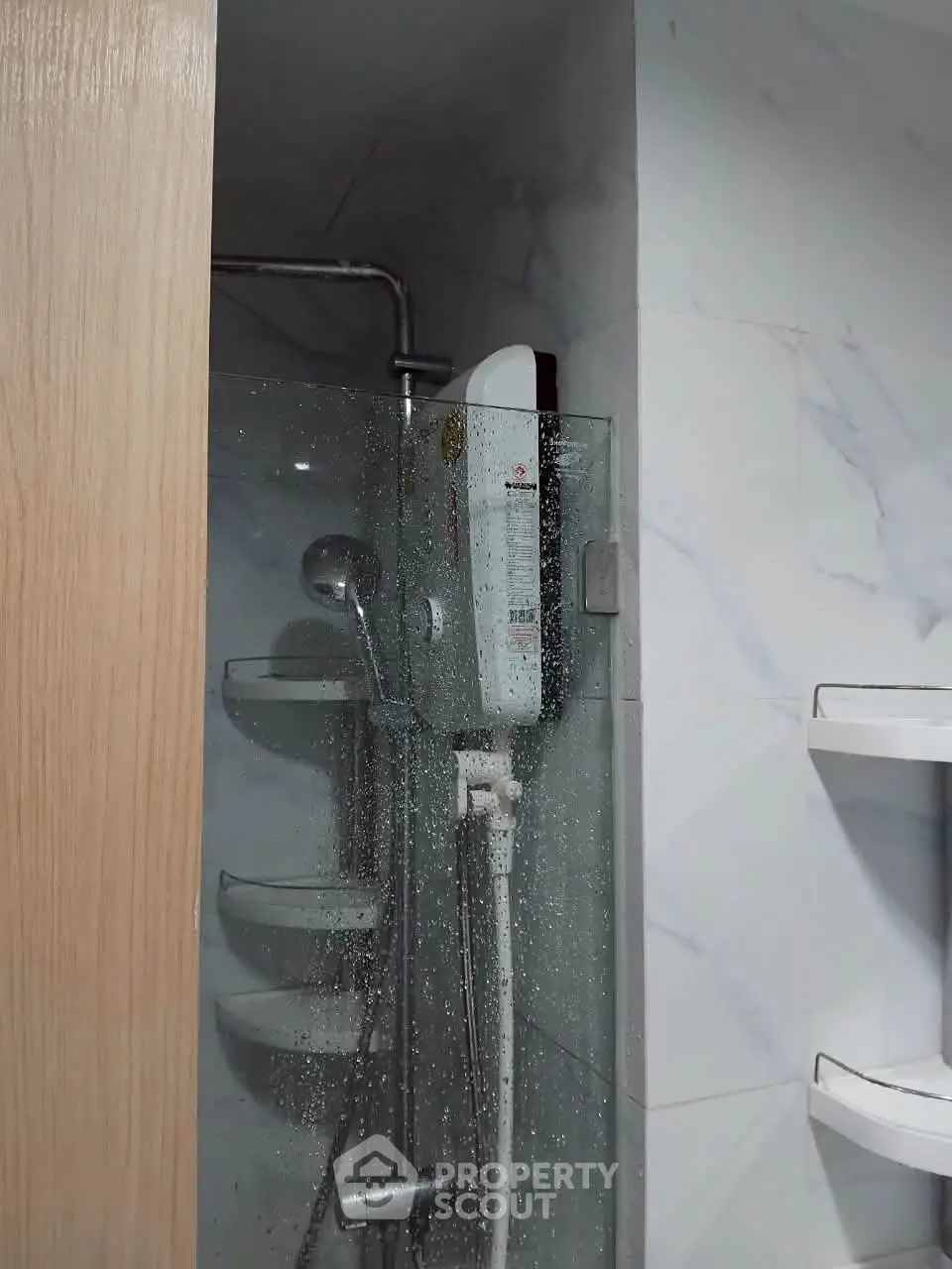Modern bathroom with sleek shower and marble tiles, featuring a compact water heater.