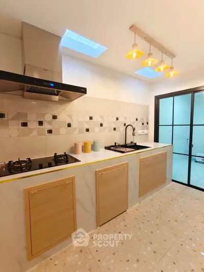 Modern kitchen with sleek design, gas stove, and stylish lighting in a contemporary home.
