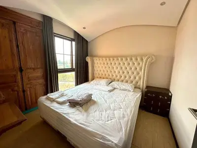 Cozy bedroom with elegant tufted headboard and rustic wooden wardrobe, perfect for relaxation.
