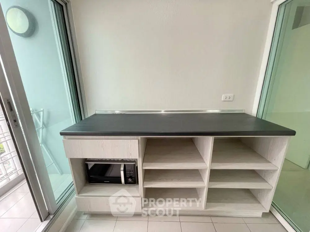 Modern kitchen with sleek countertop and built-in microwave, surrounded by glass doors for natural light.