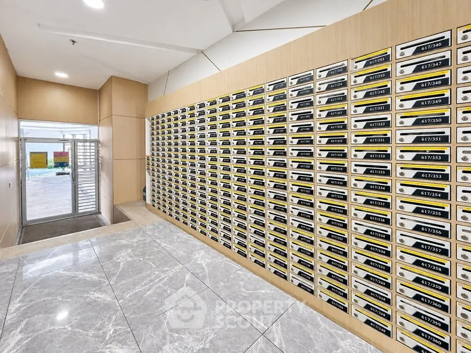 Modern apartment building mailroom with sleek design and numerous mailboxes.