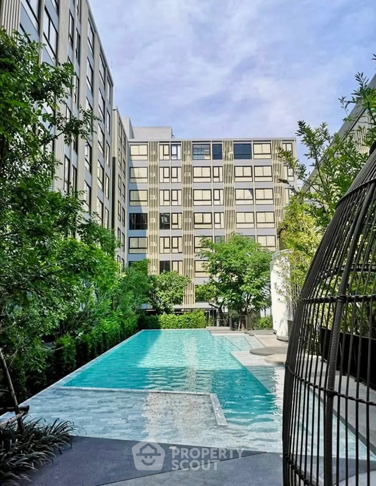 Luxurious apartment complex with a stunning outdoor pool and lush greenery.