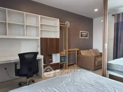 Modern bedroom with study area, featuring sleek desk and comfortable sofa.