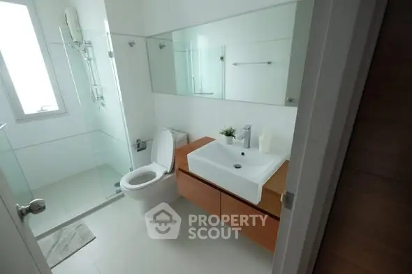 Modern bathroom with glass shower and sleek vanity in a bright, minimalist design.