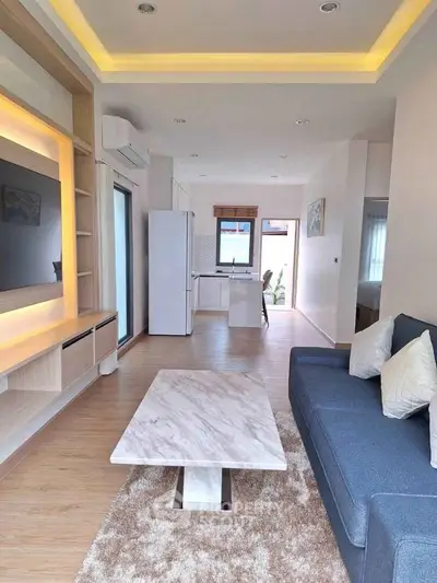 Modern living room with open kitchen, stylish furniture, and elegant lighting.