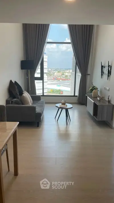 Modern living room with large window and city view, featuring stylish furniture and decor.