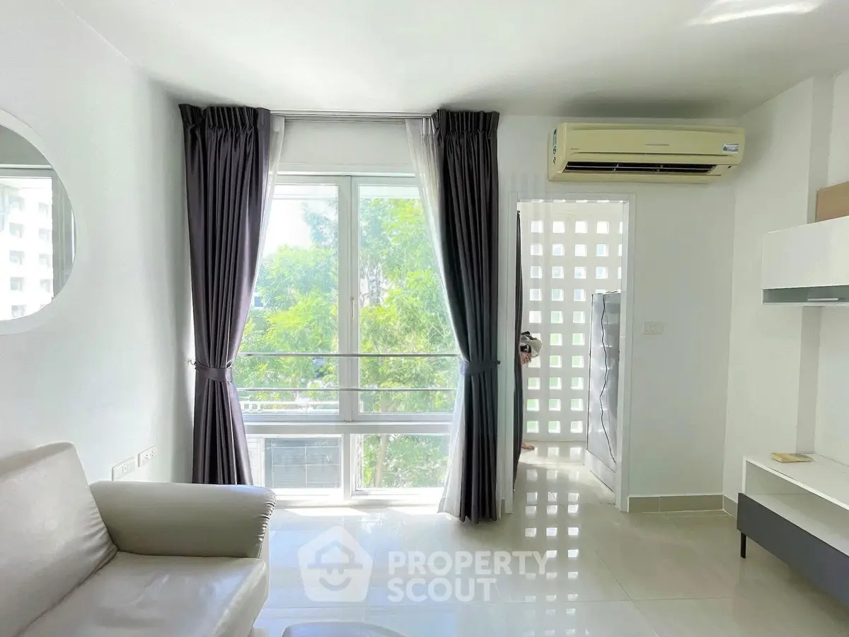 Bright and modern living room with large window and air conditioning unit, perfect for relaxation.