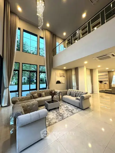 Luxurious double-height living room with elegant chandeliers and plush sofas, offering a sophisticated ambiance.