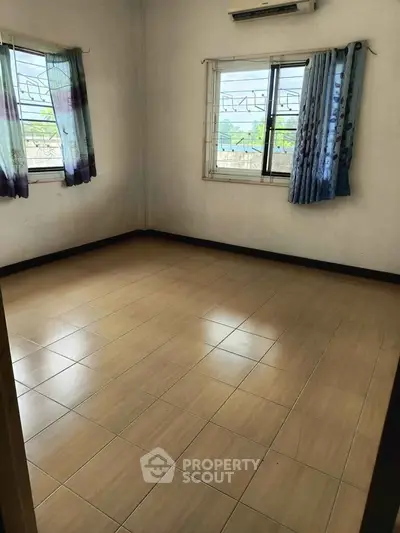 Spacious empty room with tiled floor and large windows, perfect for customization.