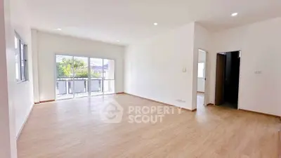 Spacious empty living room with large windows and wooden flooring, perfect for customization.