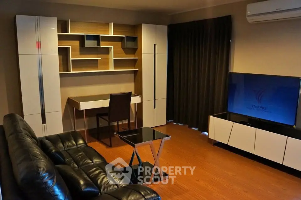 Modern living room with sleek furniture and built-in shelving, featuring a stylish desk and large TV.