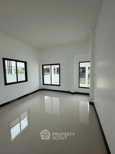 Spacious unfurnished room with large windows and glossy tiled floor, perfect for customization.