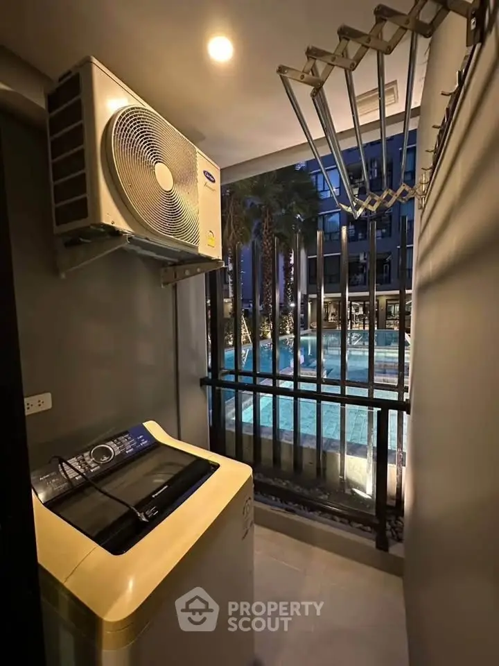 Modern condo laundry area with pool view, featuring washing machine and air conditioning unit.