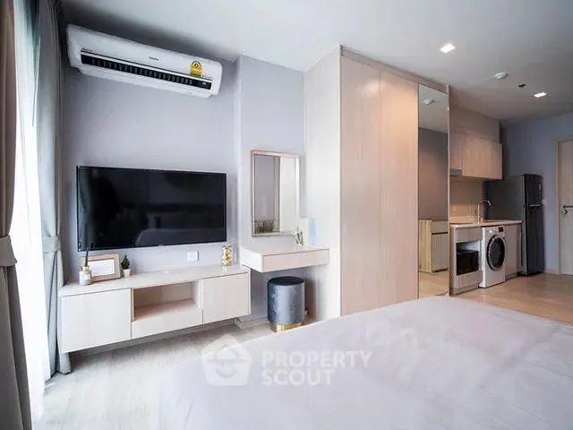 Modern studio apartment with sleek design, featuring a wall-mounted TV, air conditioning, and compact kitchen.