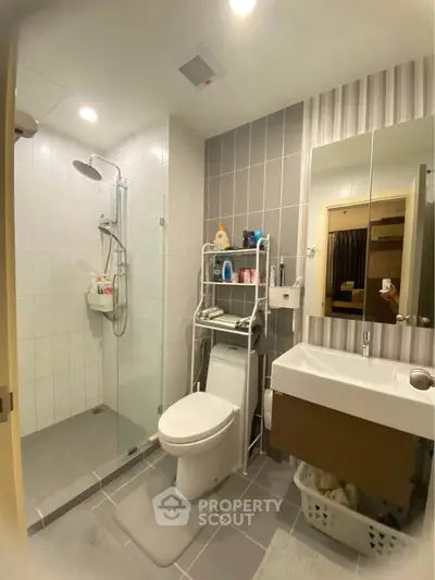 Modern bathroom with glass shower and sleek fixtures in contemporary apartment.