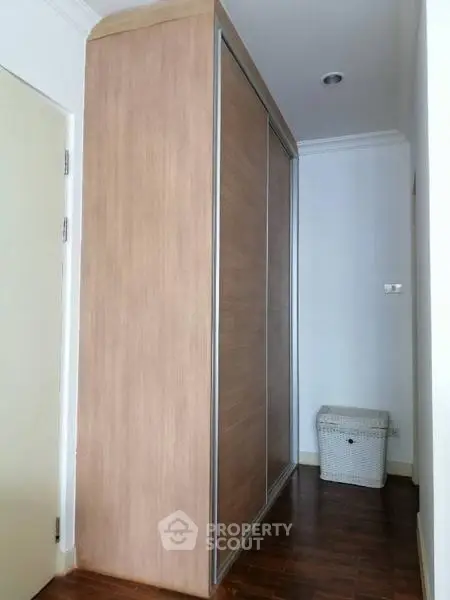 Spacious storage area with modern wooden wardrobe and wicker basket