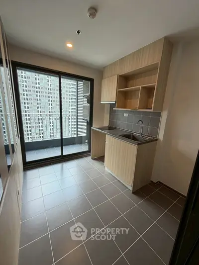 Modern kitchen with sleek cabinetry and balcony view in high-rise apartment
