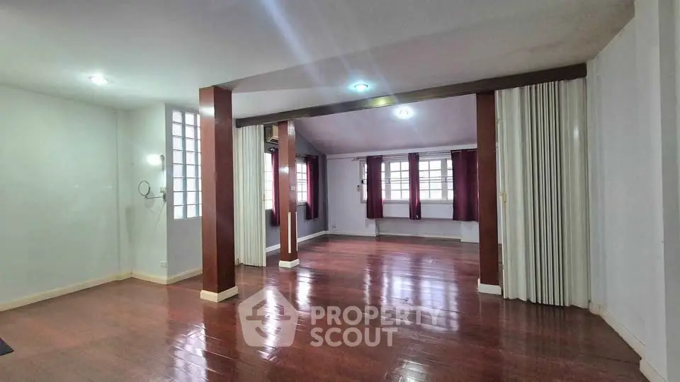 Spacious open-plan living room with polished wooden floors and ample natural light.