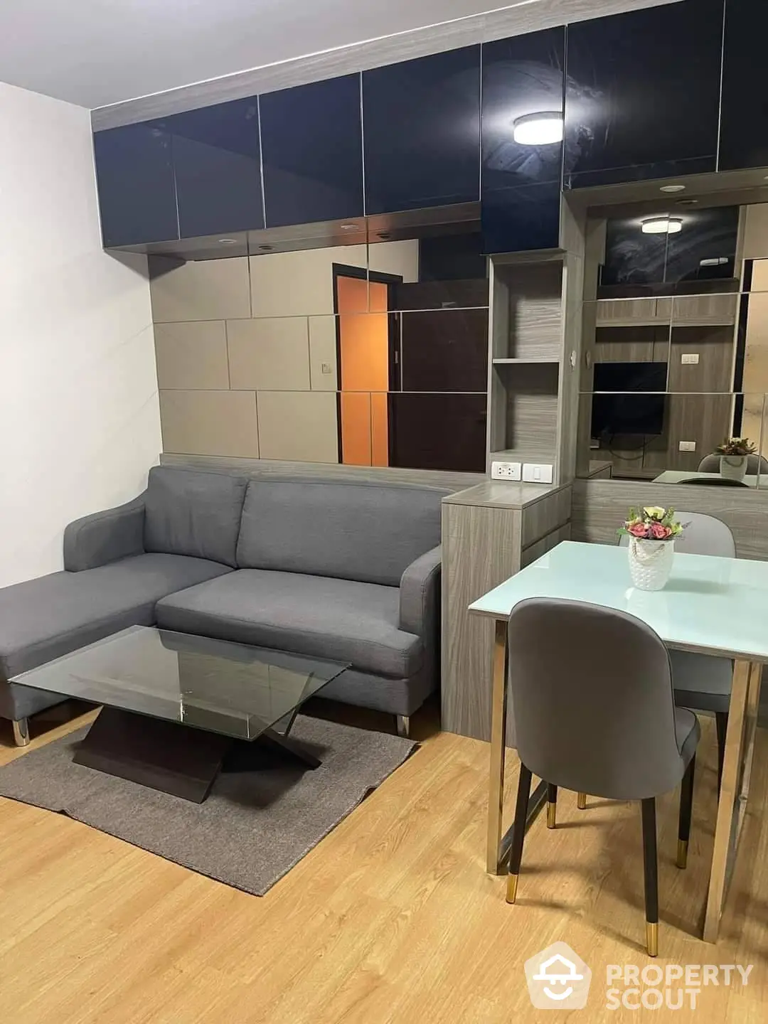 Modern living room with sleek grey sectional sofa, matching dining area, and elegant built-in cabinetry, perfect for urban living.