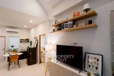 Modern living room with open kitchen, stylish shelves, and sleek decor in a cozy apartment.