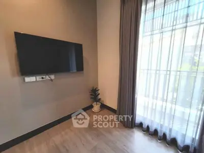Modern living room with wall-mounted TV and large window with sheer curtains