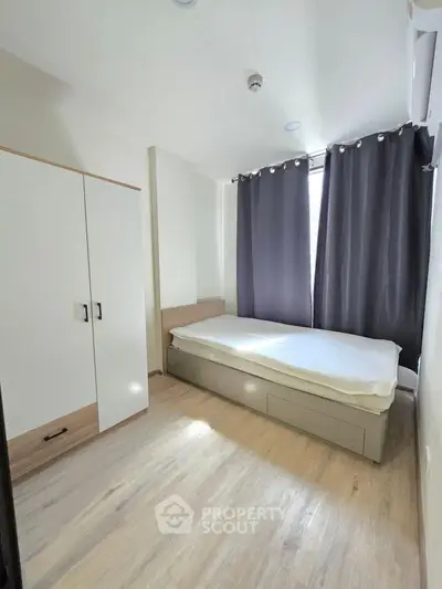 Modern bedroom with minimalist design, featuring a single bed, wardrobe, and large window with curtains.