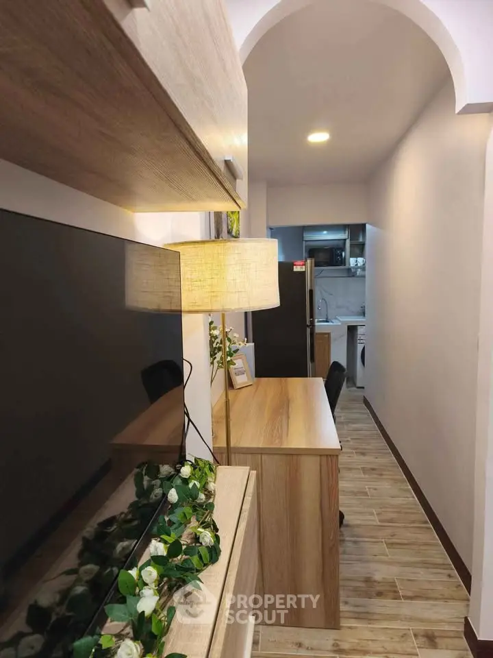 Chic and modern hallway with stylish wooden furniture and ambient lighting leading to a compact kitchen.